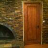 Rustic ledger panel fireplace and wall around door.