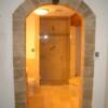 Travertine arch with black granite key stone leading into a luxurious master bathroom.