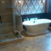 Very Elegant travertine and marble combination in master bathroom with vintage marble pattern on wall behind tub.  Steam shower to the left.